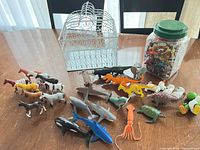 overview of bird cage, jar and spread of animal figurines on table