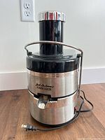 Front view of Jack LaLanne's Power Juicer showing spout, logo, locking arm, and power cord