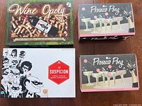 All four game boxes: Wine-Opoly, Suspicion, two Prosecco Pong