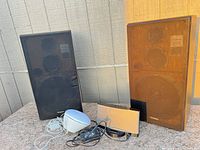 Pair of Technics speakers with grilles attached beside Bose dock, Philips radio and cables