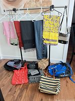 Full view of rack with scarves, bags on hangers and multiple bags on floor