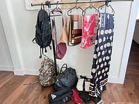 Assorted bags, backpacks, scarf and gloves on rack and floor including Michael Kors weekender