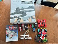 Overall lot showing race set box, book and multiple vehicles