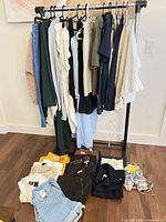 Full view of clothing rack with hanging garments and folded items on floor