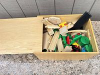 Wooden storage box partially filled with assorted track pieces and accessories