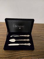 Set of three silver-plated cheese knives in open Bombay case
