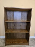 Front view showing three shelves and woodgrain finish