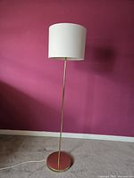 Full view of floor lamp showing gold base, pole, shade, and cord