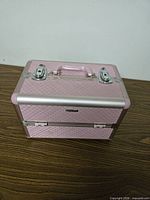 Closed pink quilted train case showing top handle and latches