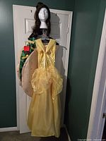 Yellow Belle dress, taco tunic and Belle wig on hanger front view