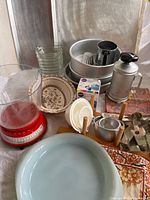 Overview of lot showing pie plate, scale, cake pans, cookie press, measuring cups, gelatin mold, sherbet dishes, cookie sheet and other items
