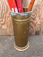 Full view of brass stand with red umbrella and cane