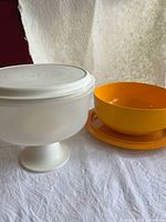 White cake carrier beside orange bowl on platter