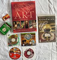 Group shot showing all items: comic, book, tarot deck, small red box and three PC game discs