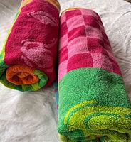 Two rolled multicolour beach towels showing ends and pattern