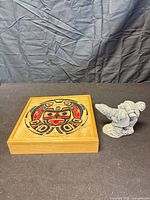 Wood box with circular Indigenous artwork and Arctic figurine beside it
