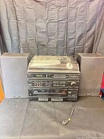 Stereo main unit with attached cord flanked by two speakers