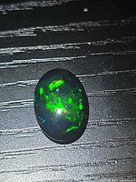 Front view of oval Ethiopian black opal showing green fire