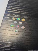 Nine oval opal cabochons on dark surface