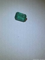 Emerald-cut green gemstone on white background