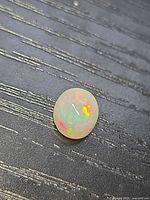 Top view of oval opal showing vivid red, green, orange flashes