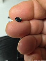 Gemstone held between fingers displaying size and colour