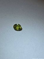 Loose oval green-yellow sapphire on white background