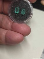 Pair of emeralds in gem jar, showing size and color