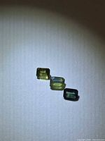 Three emerald-cut multicoloured sapphires under spotlight