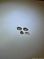 All four loose gemstones grouped on neutral background