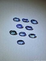 Nine oval-cut violet-blue tanzanites displayed on neutral background