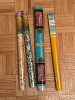 Four sealed rolls of decorative contact paper laid out on wood floor