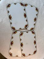 Stacked rectangular placemats showing floral borders and wear