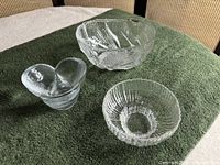 Three clear glass items: faceted bowl, ribbed candle holder, double-heart dish