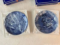 Two blue plates in styrofoam beneath their boxes