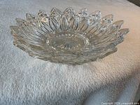 Side view of one pressed glass serving bowl showing scalloped petal rim and starburst base