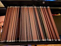 Drawer view showing rows of brown hanging folders with metal rails