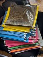 Stack of assorted colour hanging file folders showing rails and hooks