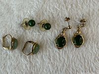 All three pairs of jade earrings displayed on fabric background
