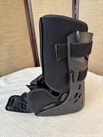 Left side view of black CAM walking boot showing straps and liner