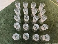 All 24 pinwheel crystal shot glasses arranged on towel, top view