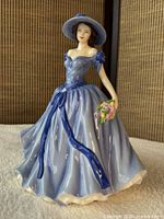 Front view of Victoria figurine in blue gown holding bouquet
