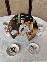 Front view showing portrait tin, two mugs, two dishes