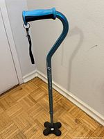 Full view of cane showing handle, shaft branding, and quad base