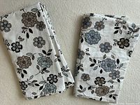 Both folded shower curtains showing floral print