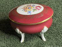 overall view of closed trinket box showing colour, floral lid and tripod legs