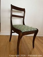 Front angled view showing wood frame and green patterned seat