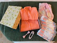 Lot overview: sweaters in box, packaged shirts, rattles, floral lid
