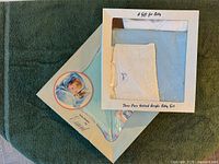 Two boxed baby gift sets showing blankets and shirts