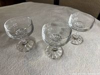 Three crystal champagne coupes displayed upright on fabric surface